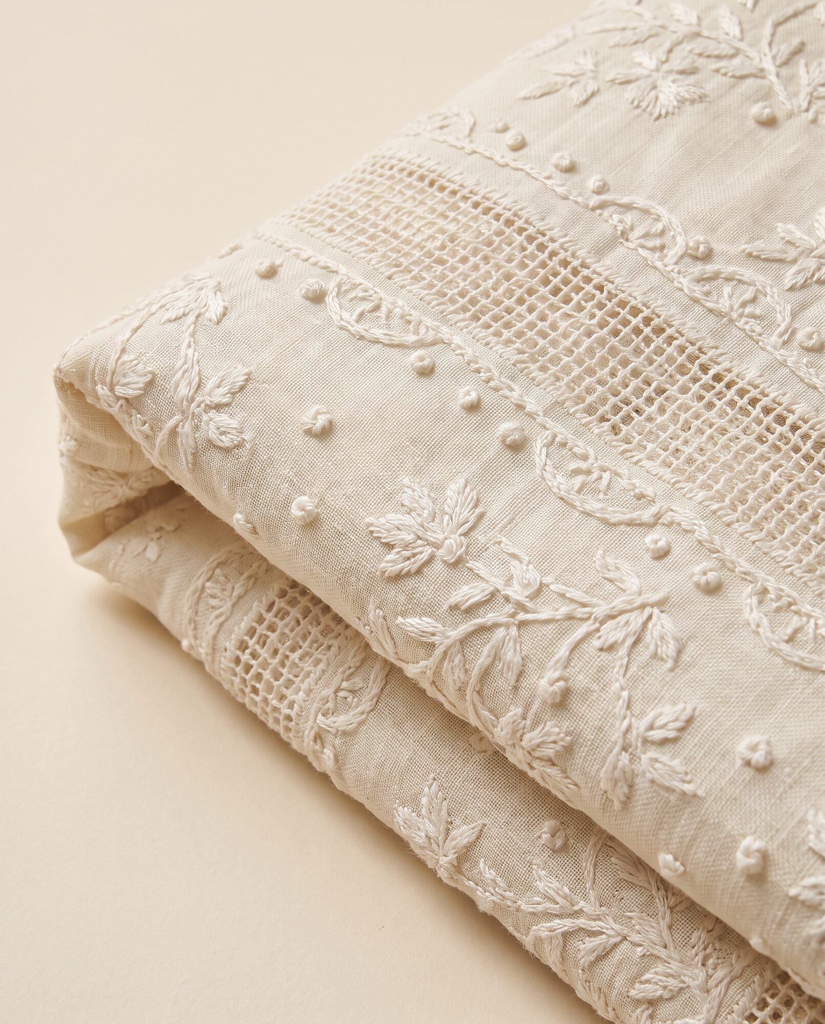 Close-up of ivory chikankari lawn showing pulled-thread jaali mesh worked by hand