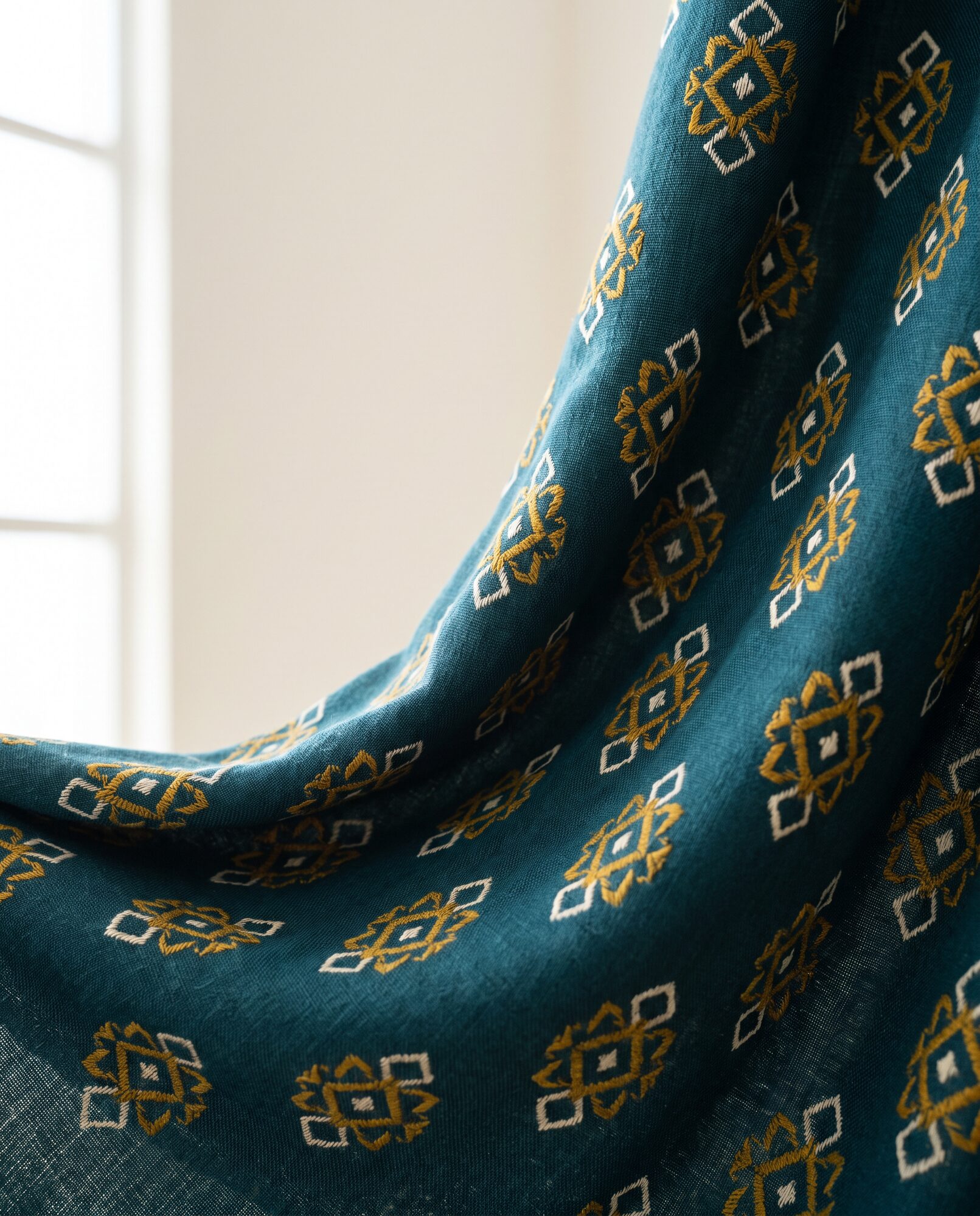 Close-up of the geometric screen print on teal viscose
